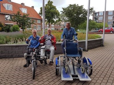Vrijwilliger Jos de Bie zit op een speciale duo-fiets met een bewoner.