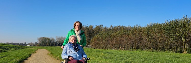 Medewerker Rivas Loopt Buiten Met Clënt In Rolstoel