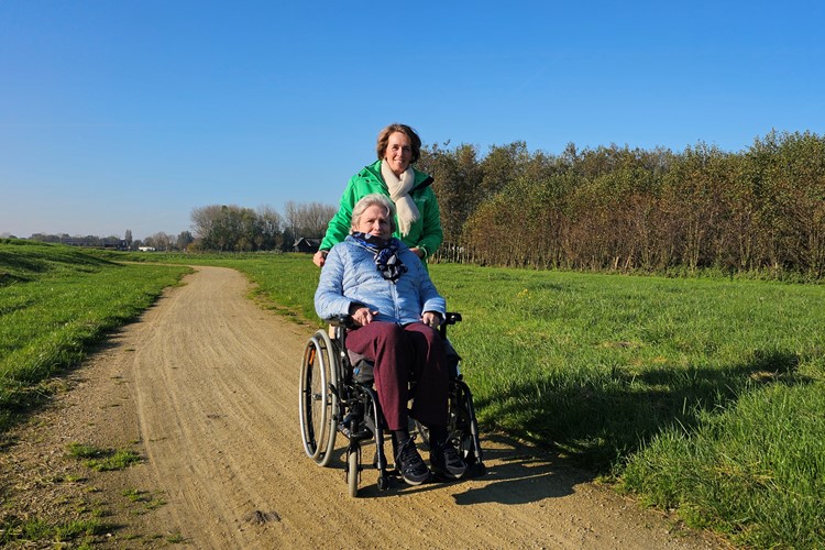 Medewerker Rivas Loopt Buiten Met Clënt In Rolstoel