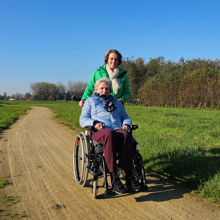 Medewerker Rivas Loopt Buiten Met Clënt In Rolstoel