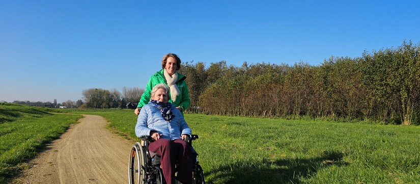 Medewerker Rivas Loopt Buiten Met Clënt In Rolstoel