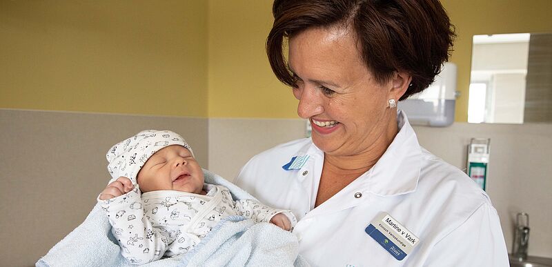 verpleegster houdt pasgeboren baby vast